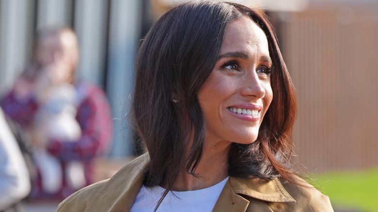 A smiling Meghan Markle looking over her shoulder