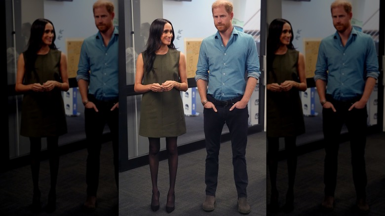 Meghan Markle in an olive green dress and black tights standing next to Prince Harry
