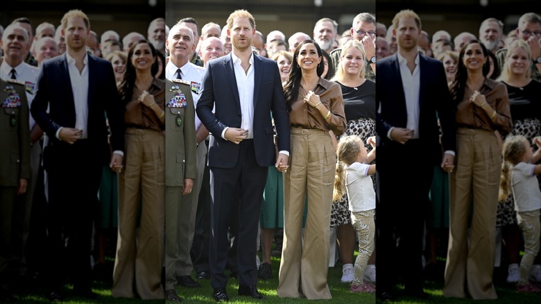 Meghan Markle smiling and holding hands with Prince Harry