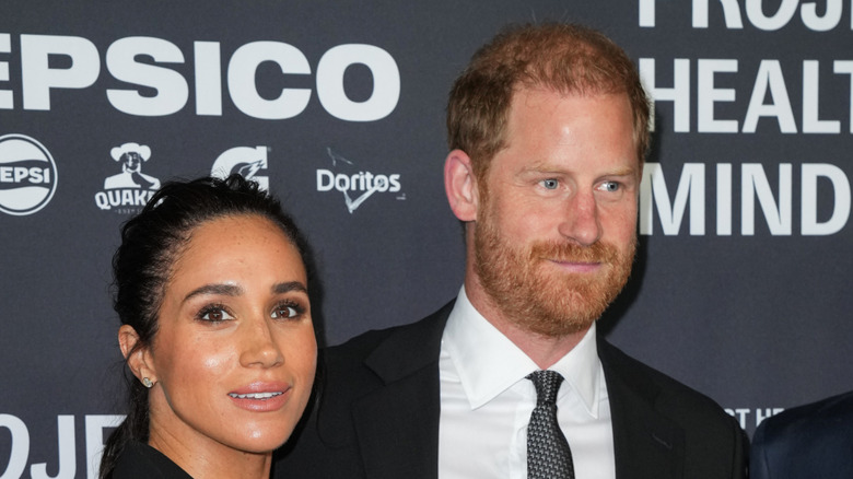 Meghan Markle and Prince Harry posing at an event in black outfits