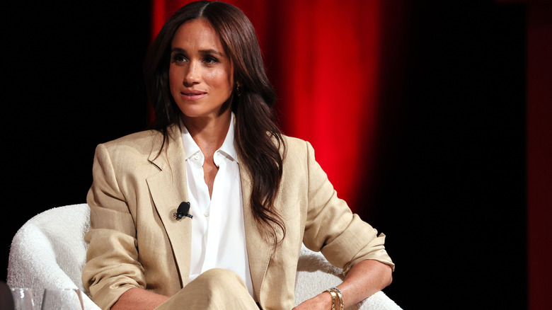Meghan Markle engaging in a conversation in a suit