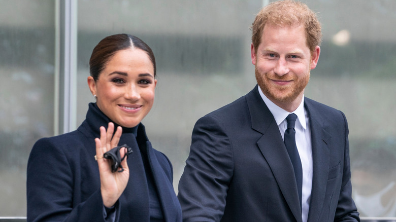 Meghan Markle and Prince Harry walking together while Meghan waves