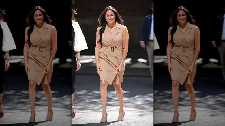 Meghan Markle smiling in a tan dress, walking outside.