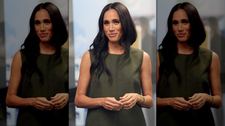 Meghan Markle wears a dark green shift dress.