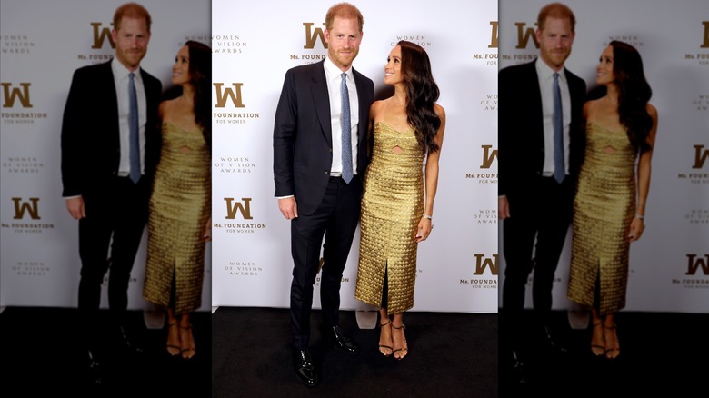 Meghan Markle wearing a gold dress and smiling at Prince Harry