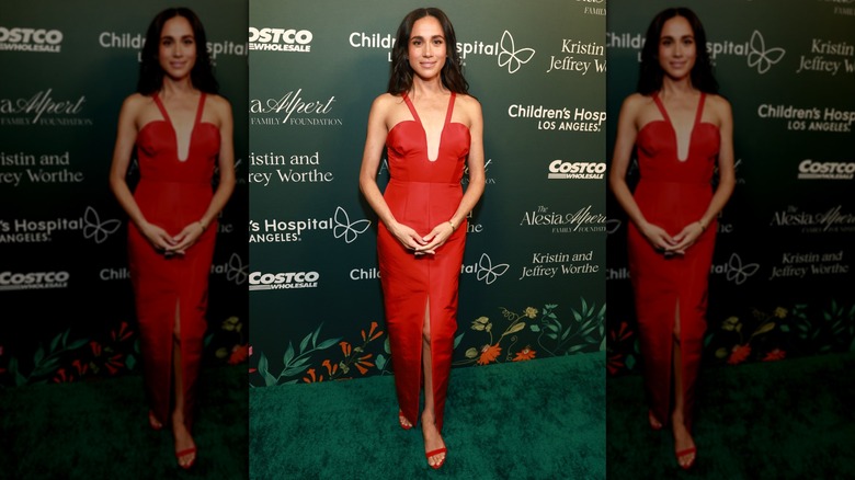 Meghan Markle posing in a red dress with a deep neckline