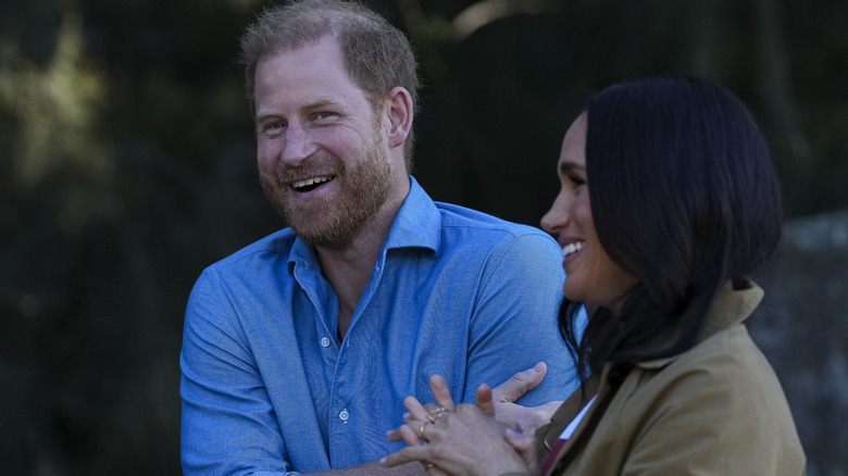 Prince Harry in blue shirt laughing with Meghan Markle in Australia