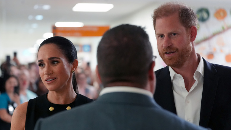 Prince Harry and Meghan Markle talking to someone