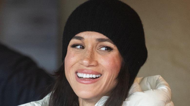 Meghan Markle smiling while wearing black cap
