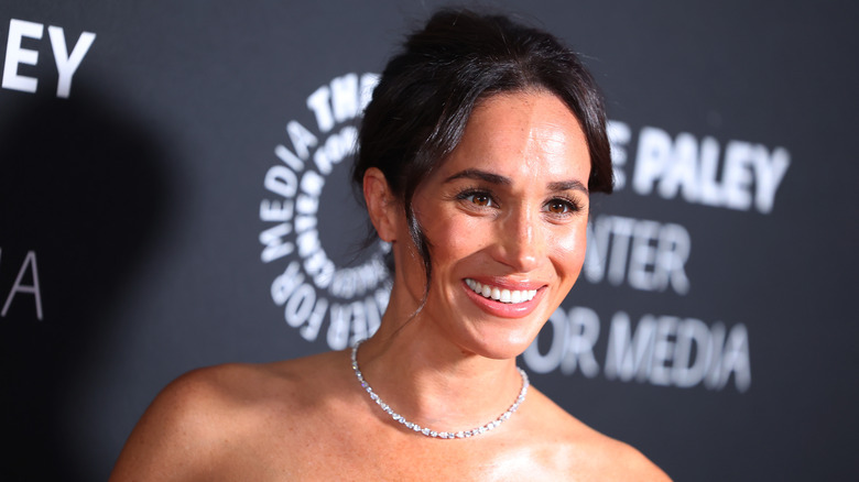 Meghan Markle smiling while wearing diamond necklace