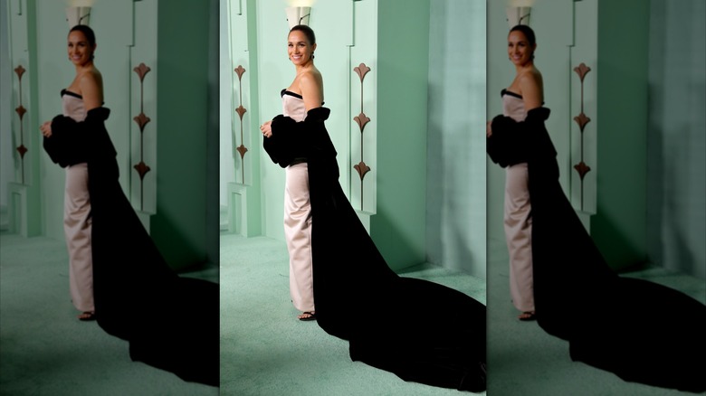 Meghan Markle smiles and poses in dress and long jacket at entertainment event