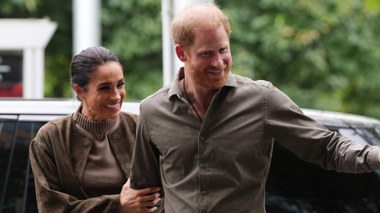 Prince Harry and Meghan Markle walking together in matching green outfits