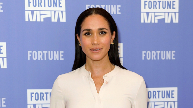 Meghan Markle posing on the red carpet in a white top