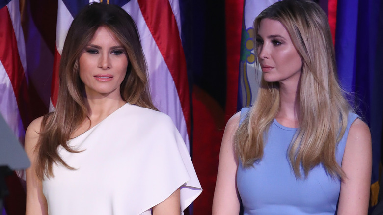 An unsmiling Ivanka Trump looking at a smiling Melania Trump
