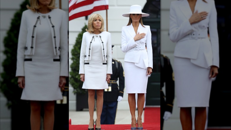 Brigitte Macron and Melania Trump posing together while wearing similar white blazers and dresses while at a White House annual ceremony.