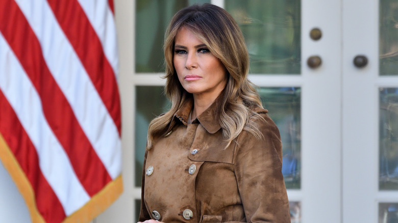 Melania Trump brown coat looking solemn