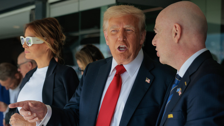 Melania Trump wearing sunglasses while standing behind Donald Trump
