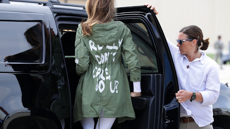 Melania Trump getting into a black car while wearing a green jacket