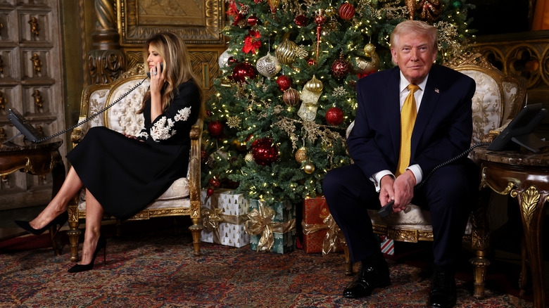 Christmas Melania Trump talking on phone Donald smiling by tree