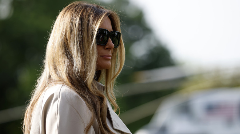 Melania Trump waits as U.S. President Donald Trump speaks to the media as they depart the White House on April 25, 2025 in Washington, DC.