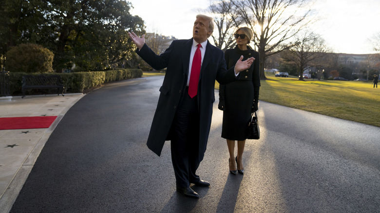 Donald Trump looking wildly excited with a bored-looking Melania Trump behind him