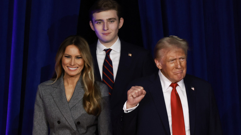 Donald Trump fist raised with Barron standing behind him and Melania stood next to him smiling