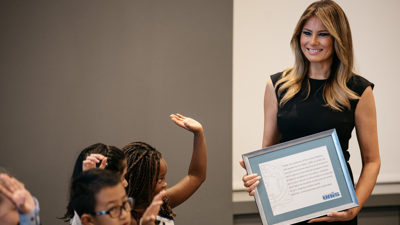 Melania Trump smiling and looking deep in thought while holding a plaque for her "Be Best" campaign