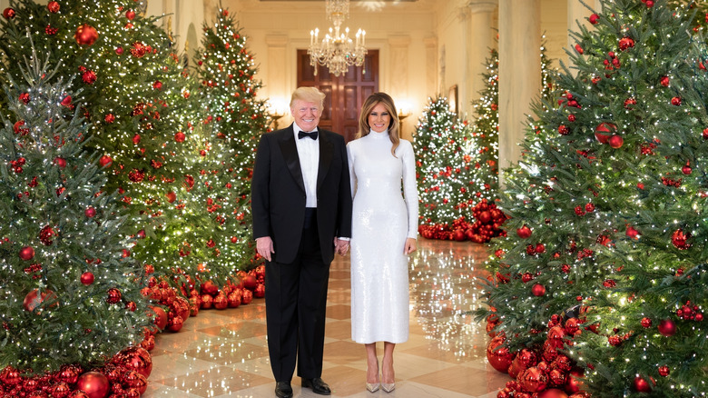 Melania and Donald Trump posing next to the White House Christmas trees