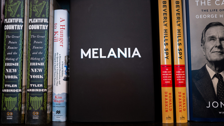 A book with the title "MELANIA" in bold white letters, displayed on a bookshelf