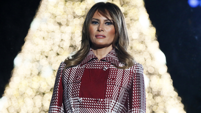 Melania Trump red plaid coat in front of Ellipse Christmas tree