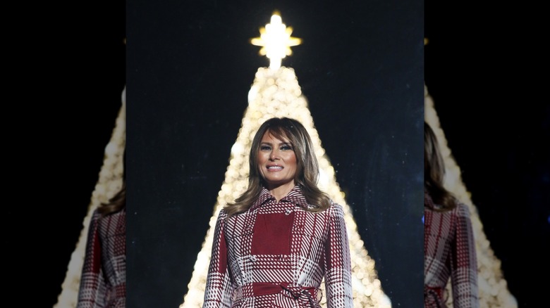 Melania Trump smiling in front of Christmas tree
