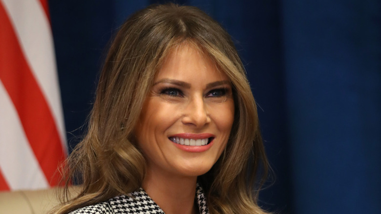Melania Trump smiling in a black and white houndstooth blazer