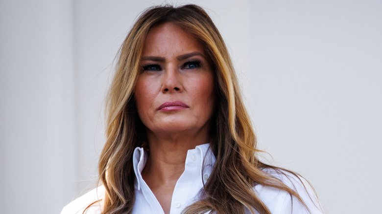 Melania Trump posing in a white buttoned-up shirt while at the White House south lawn.