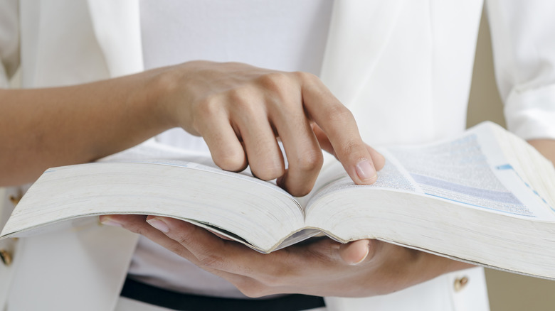 closeup of a woman's hands holding an open dictionary