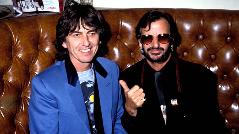 George Harrison smiling next to Ringo Starr gesturing with thumb