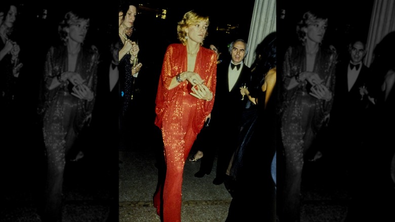 Berry Berenson attending 1979 Met Gala wearing a sparkly red plunging jumpsuit