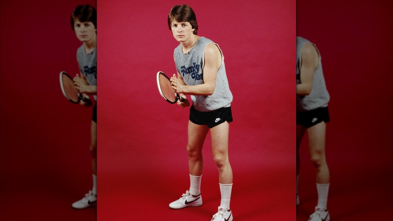 Michael J. Fox holding a tennis racket in a "Family Ties" tank top