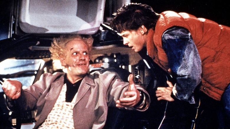 Christopher Lloyd as Doc Brown and Michael J. Fox as Marty McFly, leaning into the Delorean in "Back to the Future"