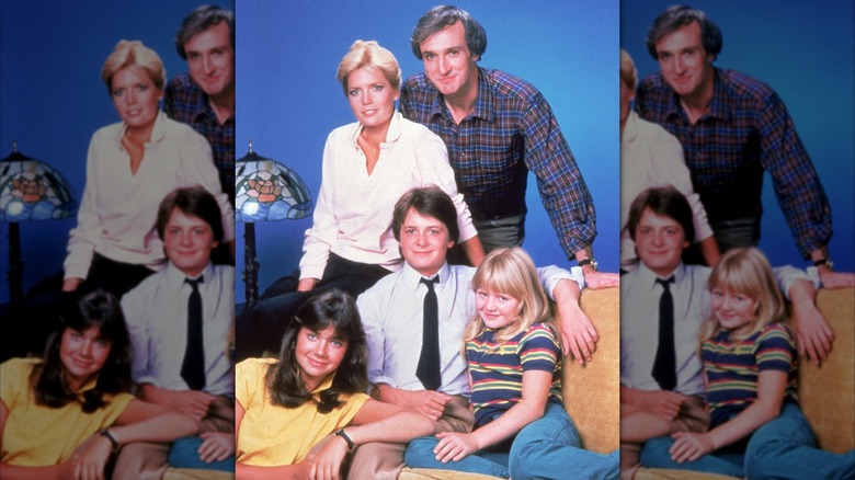 The "Family Ties" cast posing for a portrait on the couch, including Justine Bateman, Meredith Baxter, Michael Gross, Michael J. Fox, and Tina Yothers