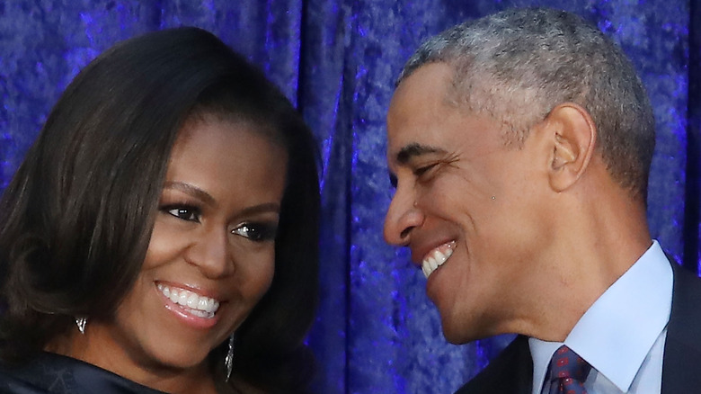 Barack and Michelle Obama smiling against a blue background