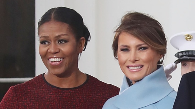 A smiling Michelle Obama and Melania Trump standing next to each other