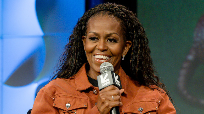 Michelle Obama smiling and talking into a microphone