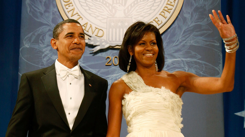 Barack Obama smiling while Michelle Obama smiles and waves