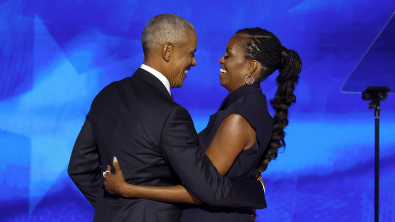 Barack and Michelle Obama smiling as they embrace onstage