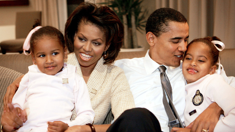 Barack and Michelle Obama cuddle with their daughters on the couch