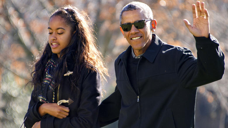 President Barack Obama waves to the assembled press as he walks with his daughter Malia on his family's return to the South Lawn of the White House January 3, 2016 in Washington, DC.