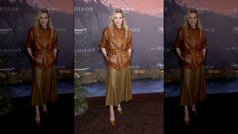 Michelle Pfeiffer in a green khaki leather skirt and brown leather button up with rolled up sleeves and a waist-cinching belt
