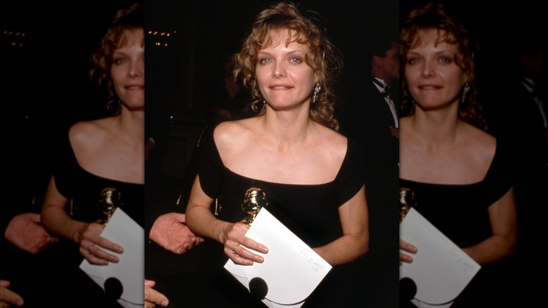 Michelle Pfeiffer with soft loose curls and black dress holding an envelope and award