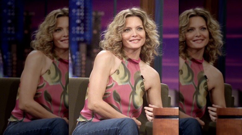 Michelle Pfeiffer in halter neck print top smiling with center part curly hair on set of "The Tonight Show."