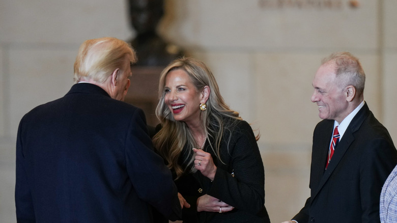 Kelly Johnson smiling and leaning towards Donald Trump